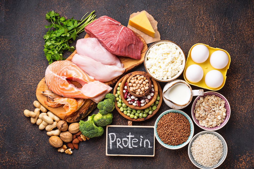 Diverse protein-rich foods arranged on a wooden surface, demonstrating healthy protein choices recommended by gut dietitian Gillian Killiner